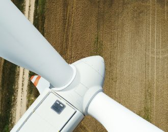 Wind turbine in operation. Close-up aerial view of a sunny European landscape.